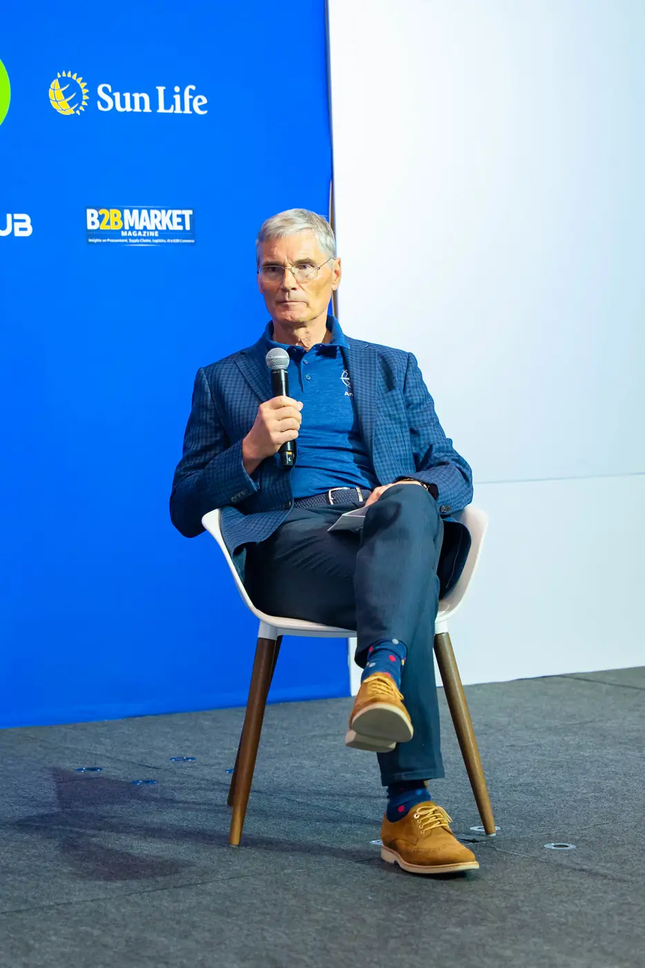 Speaker seated on stage holding a wireless microphone